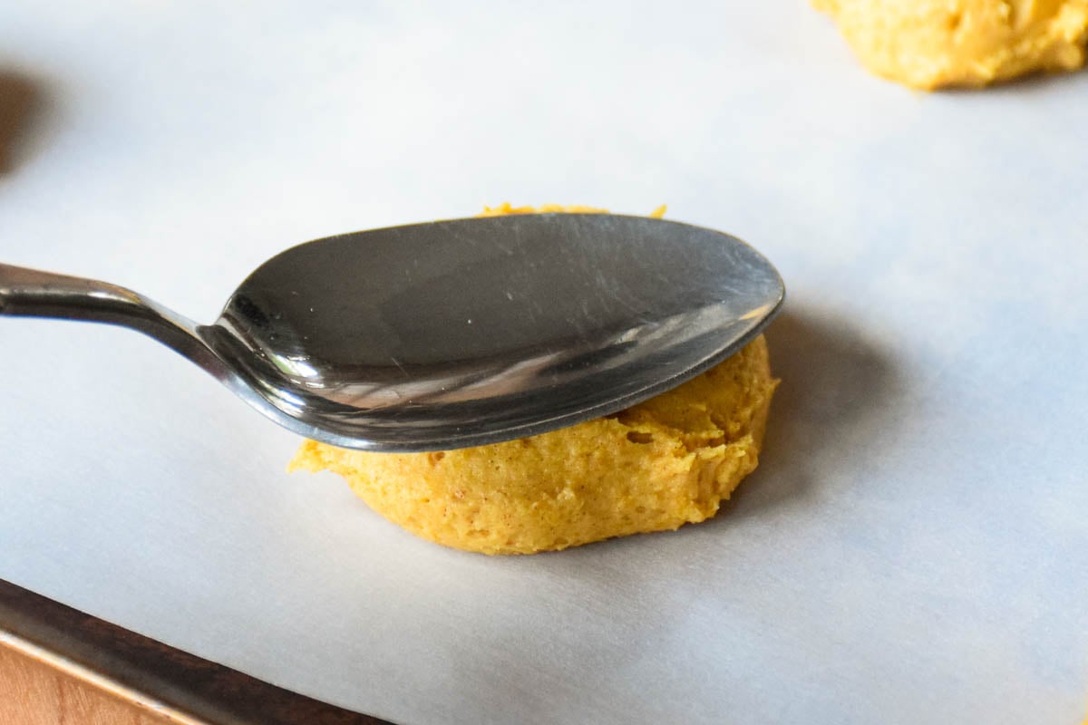 A tablespoon on top of a ball of pumpkin cookie dough.