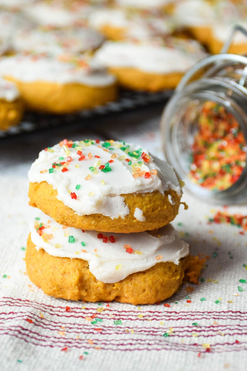 Two stacked cookies with a tray of cookies in the background.