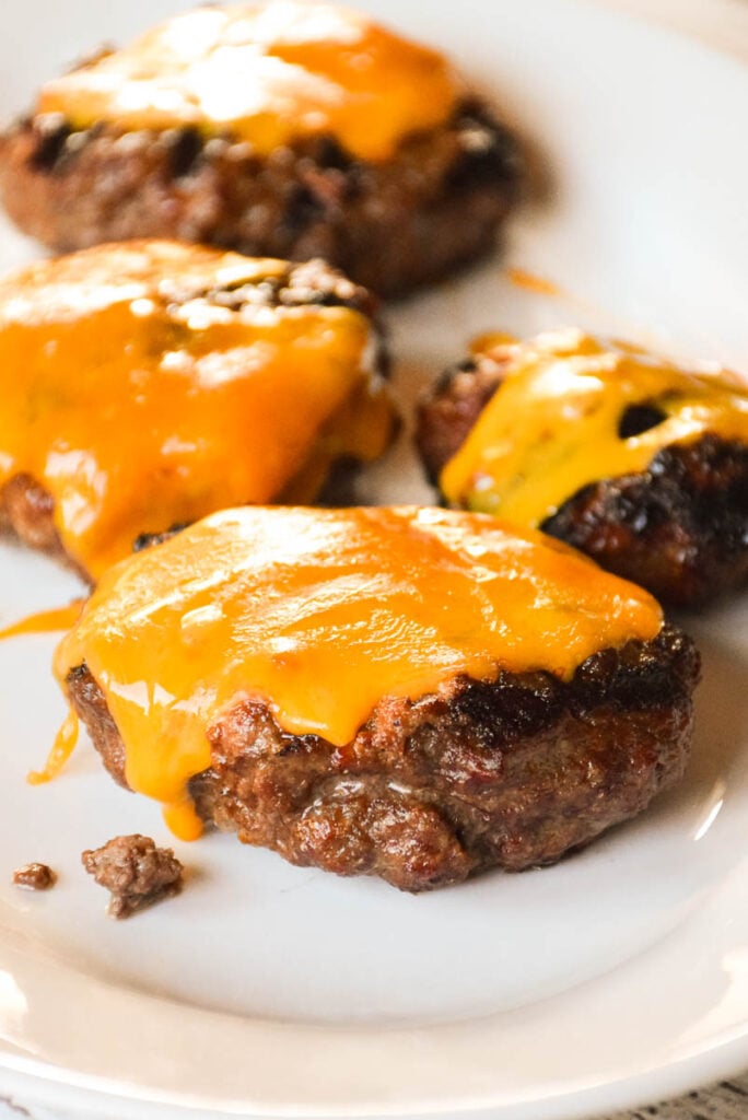 Grilled burgers topped with cheese on a white plate.