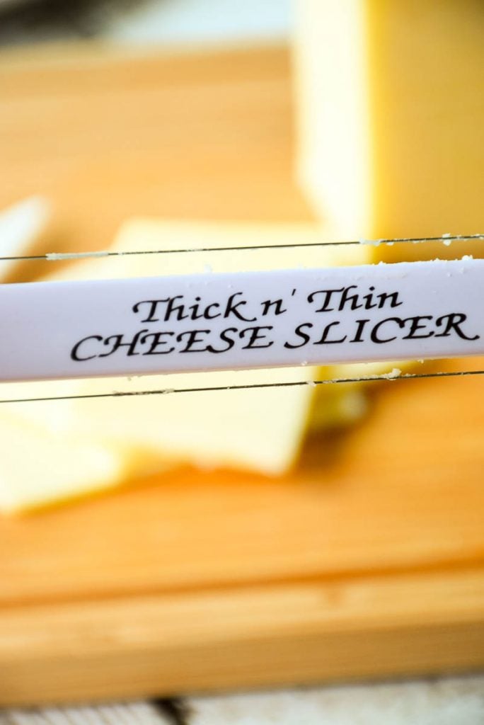 photo of thick and thin cheese slicer with sliced cheese in the background