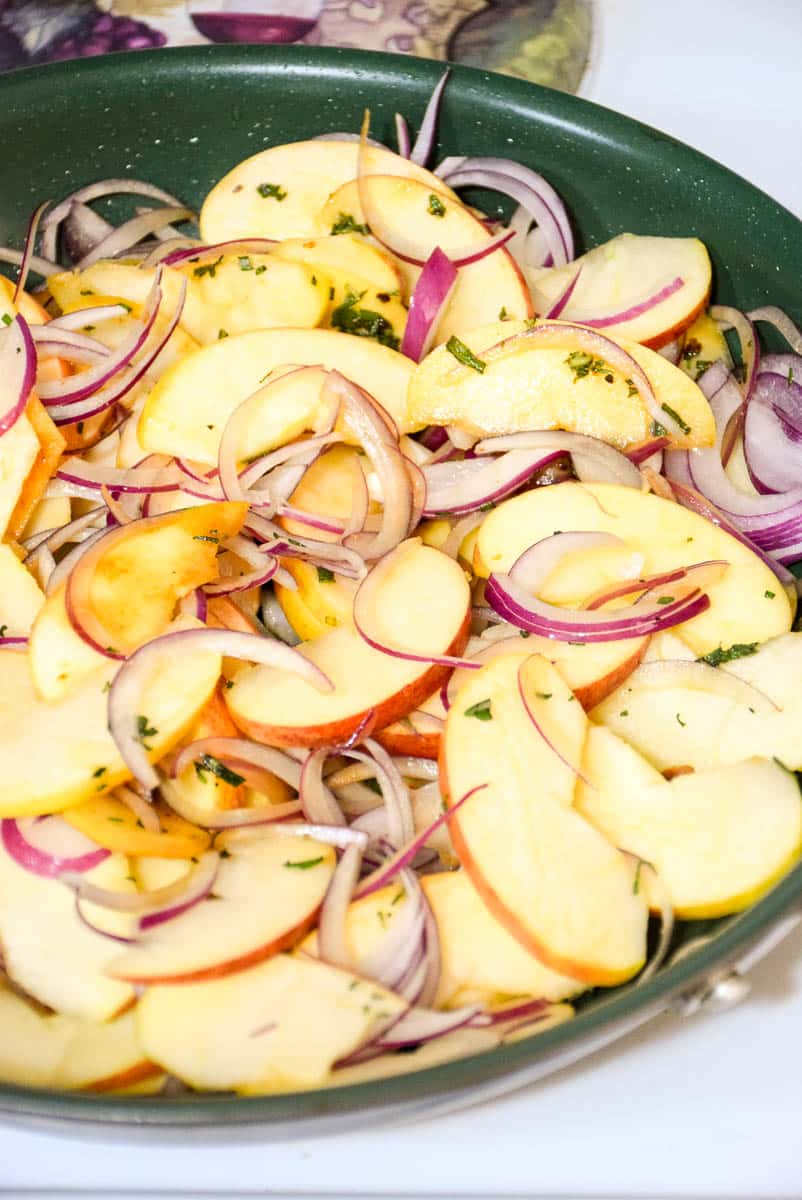 Apples and onions sauteing with seasonings in a non-stick skillet.