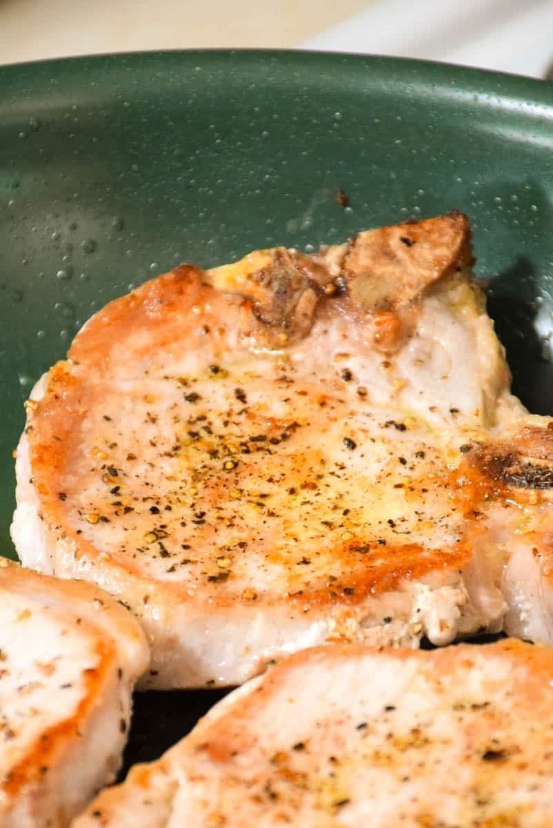 Pork chops searing in hot skillet.