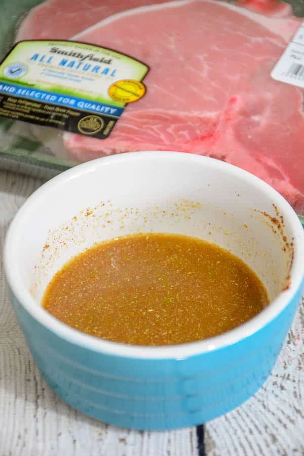 Chili lime marinade in a blue bowl with a package of unopened pork chops blurred in the background.