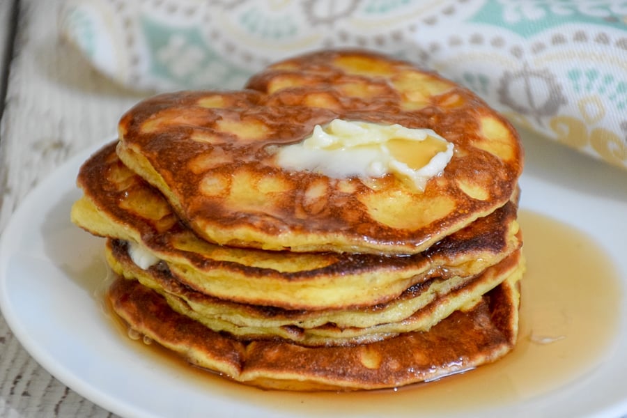 A stack of pancakes topped with butter and syrup.