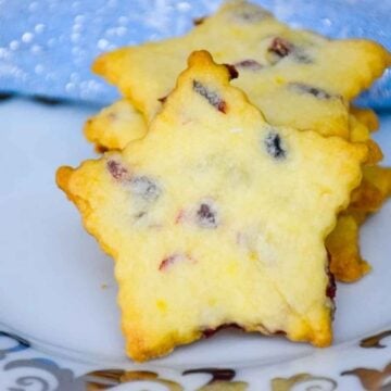 A stack of Cranberry Orange Cookies cut into star shapes with golden edges and bits of dried cranberries baked in.