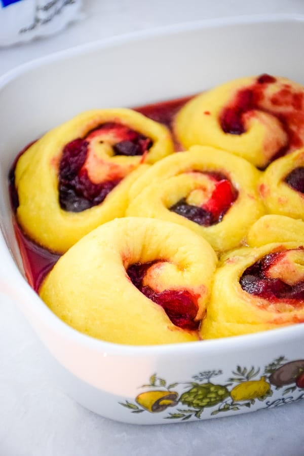 Risen and unbaked sweet rolls in a baking dish.