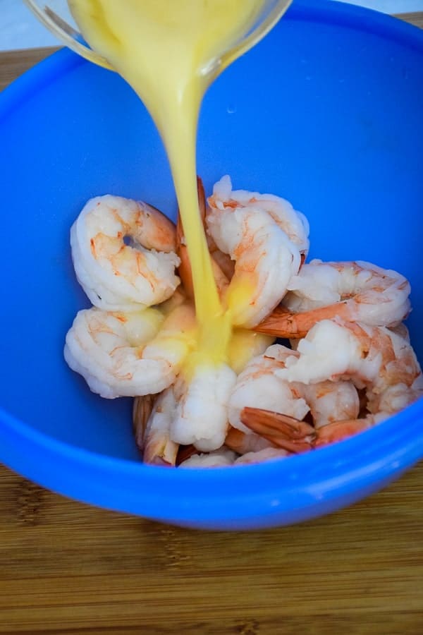 Pouring marinade over top of cooked shrimp