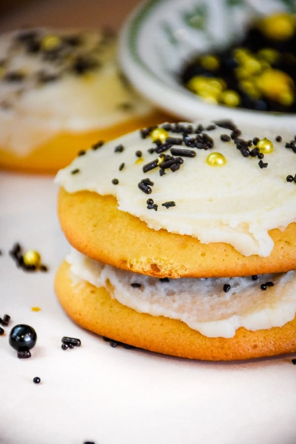 Stacked frosted cookies with gold and black sprinkles.