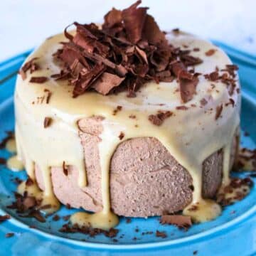 No Bake chocolate peanut butter cheesecake on a blue plate topped with peanut butter sauce and chocolate shavings.