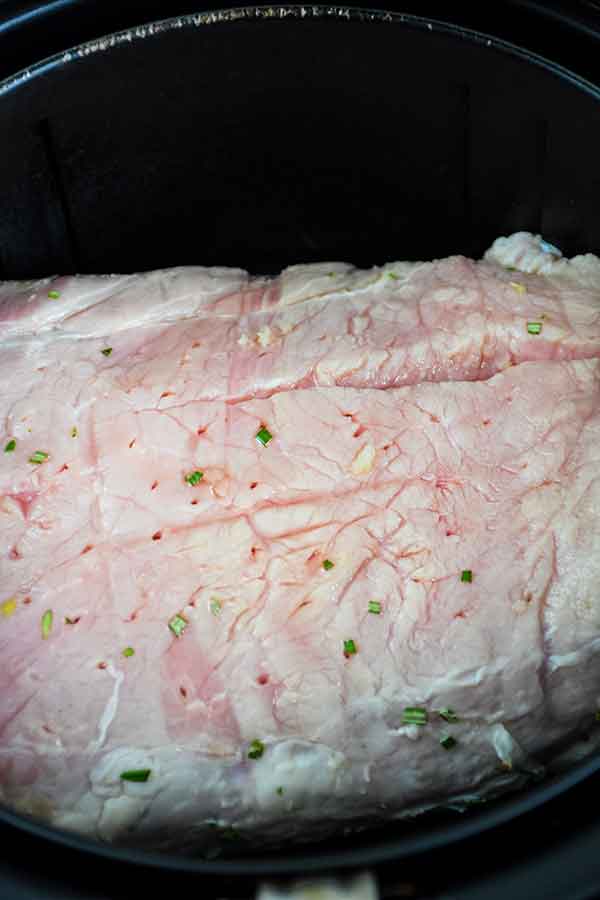 Raw pork loin roast in the air fryer basket.