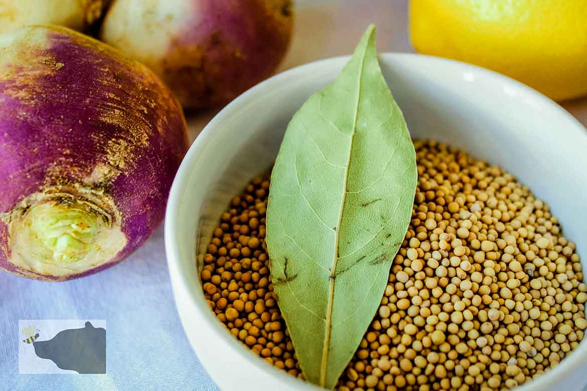 Mustard seed and bay leaf in white bowl with rutabaga beside bowl