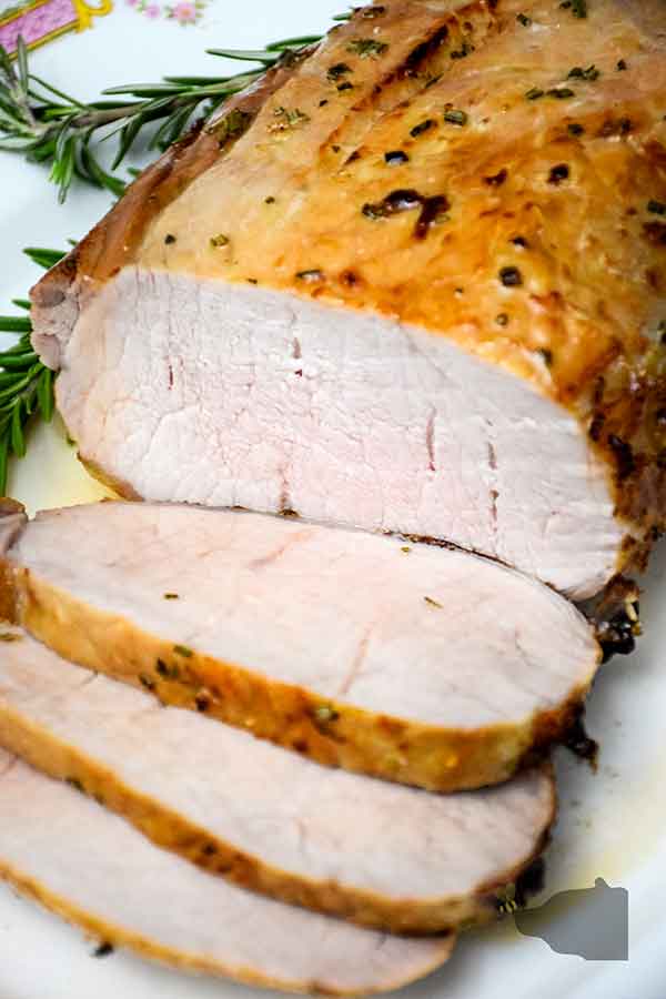 Air Fryer Maple Glazed Pork Loin on serving platter with 3 slices cut and lying in front of loin.