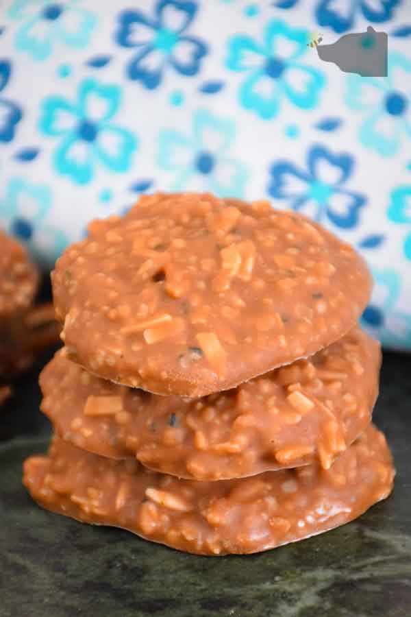 a stack of 3 keto no bake cookies with a stack of two to the left and a blue and white flowered napkin behind the cookies