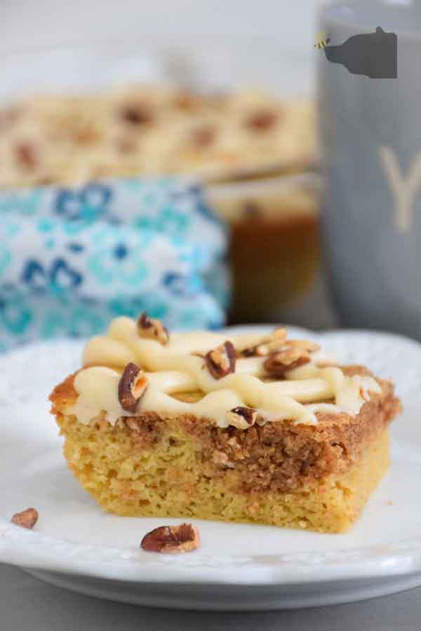 Pecan Pie Coffee Cake Slice on a white plate with whole cake in the background.