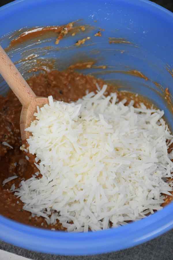 Blue mixing bowl with coconut flakes on top of peanut butter mixture