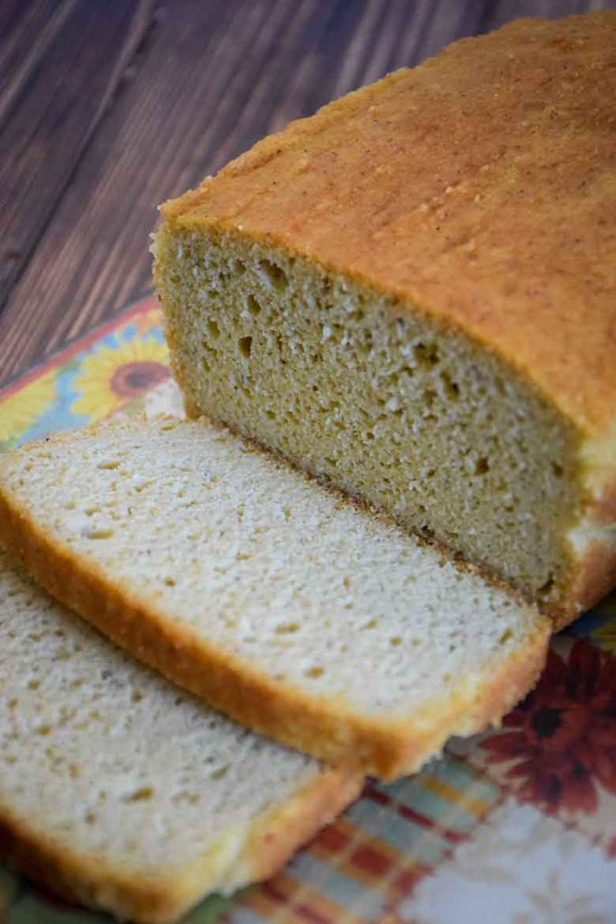 A grain free bread loaf on cutting board with two cut slices.