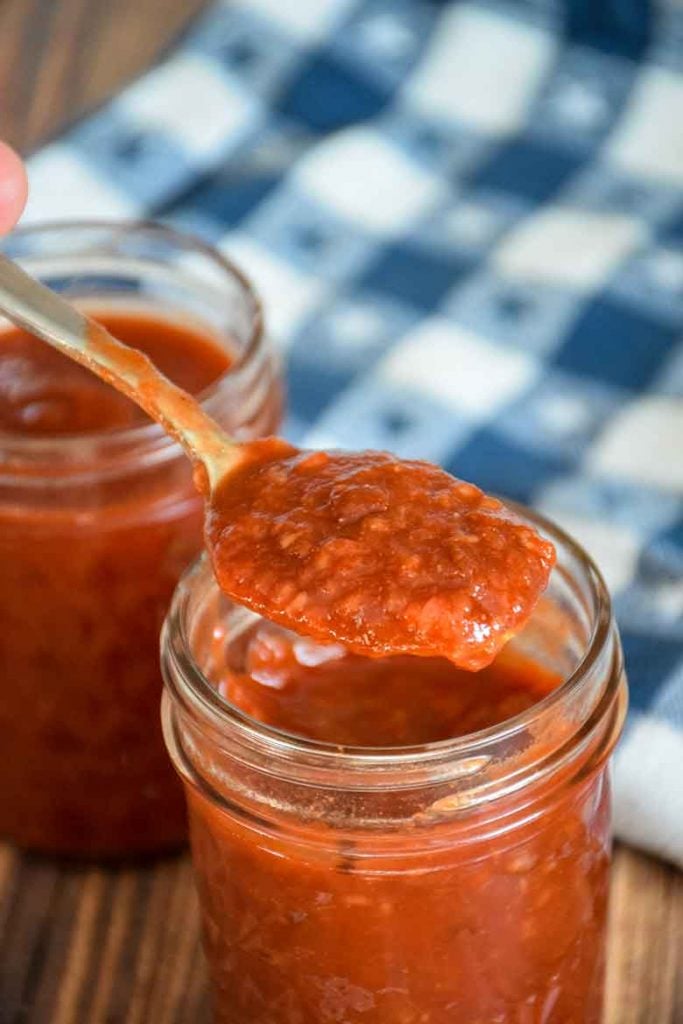 Raspberry Chipotle Sauce being spooned out of a jar with a white and blue star towel in the background