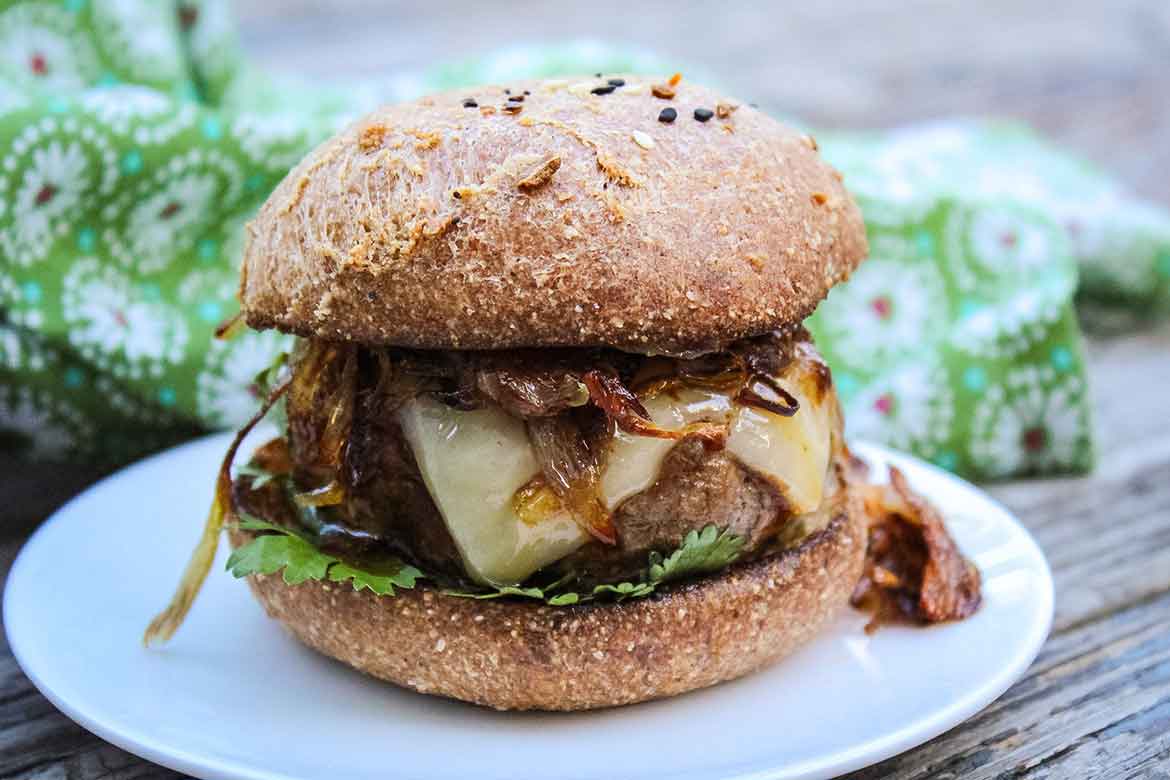 Barbecue Sauce glazed Chipotle Burger topped with cheese and crispy shallots with fresh cilantro on a keto burger bun