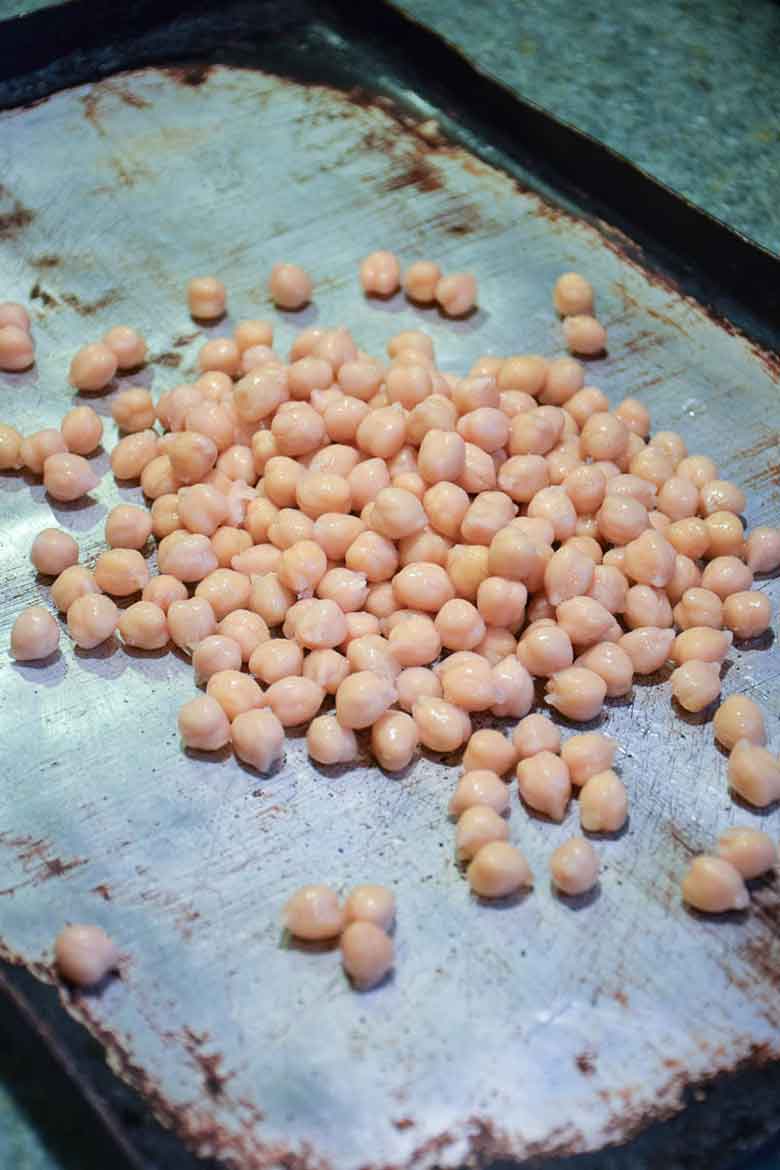 A baking sheet with drained chickpeas on top.