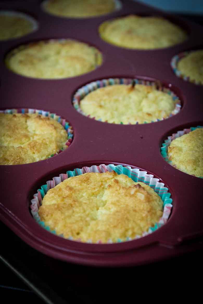 Baked cupcakes in a red silicone muffin pan on cooling rack