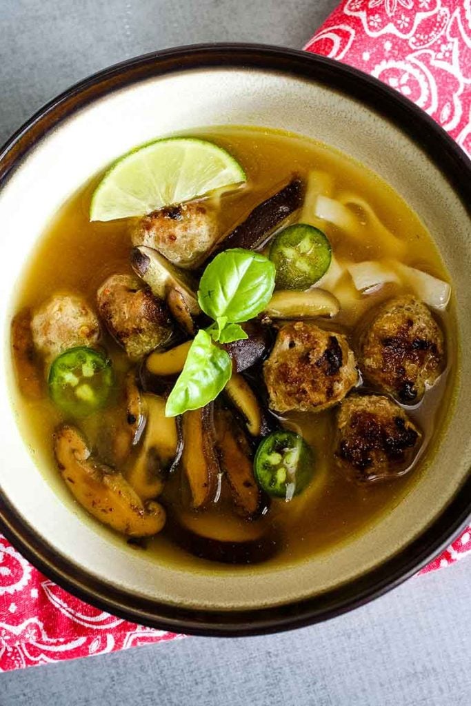 Overhead view of Pho Soup with Veal Meatballs and jalapeno, basil and lime garnish