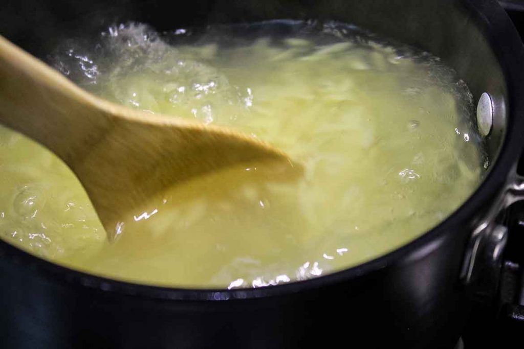 Stirring the orzo in the cooking pot.