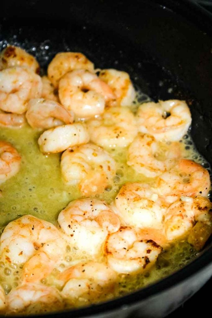 Shrimp cooking in lemon butter in a skillet.