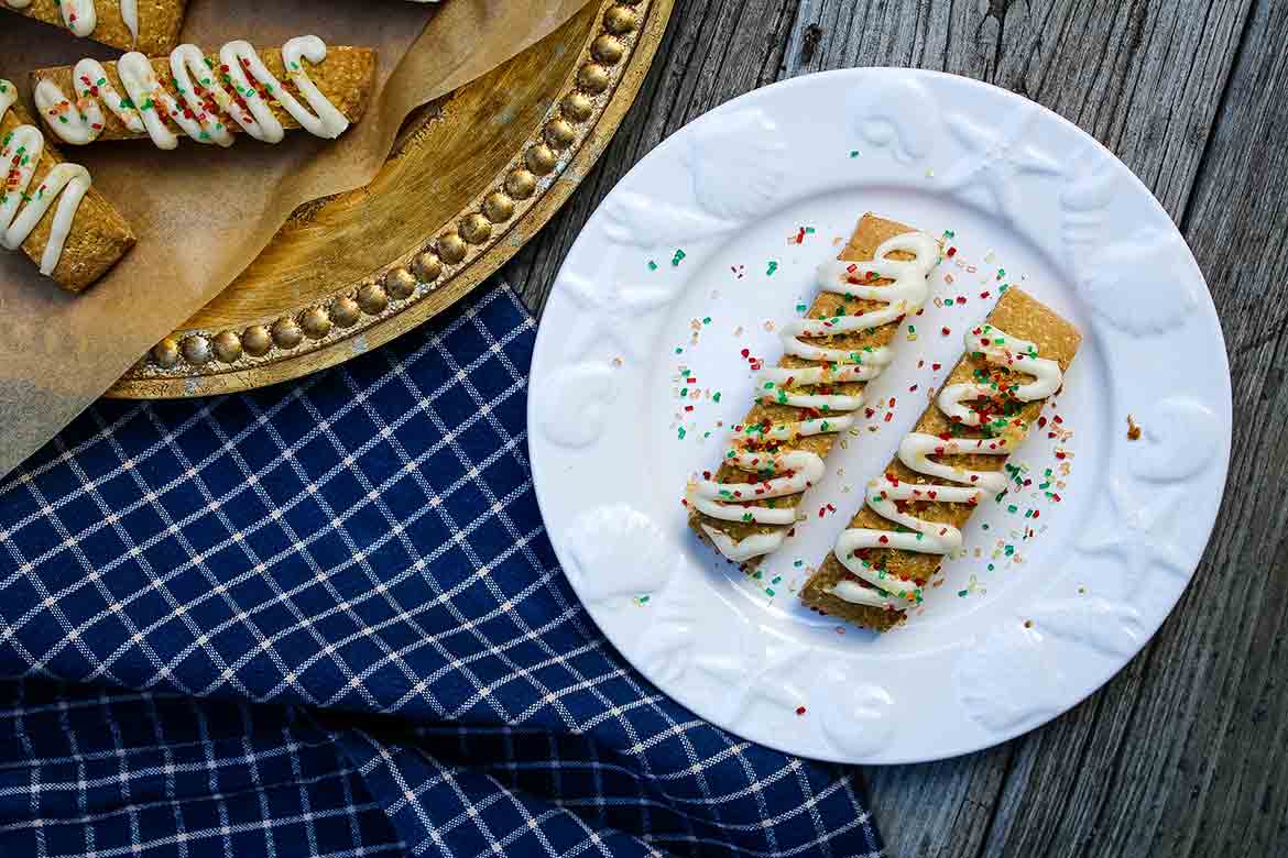 Two Pumpkin Biscotti on a plate with a tray of biscotti to the upper left on a blue towel