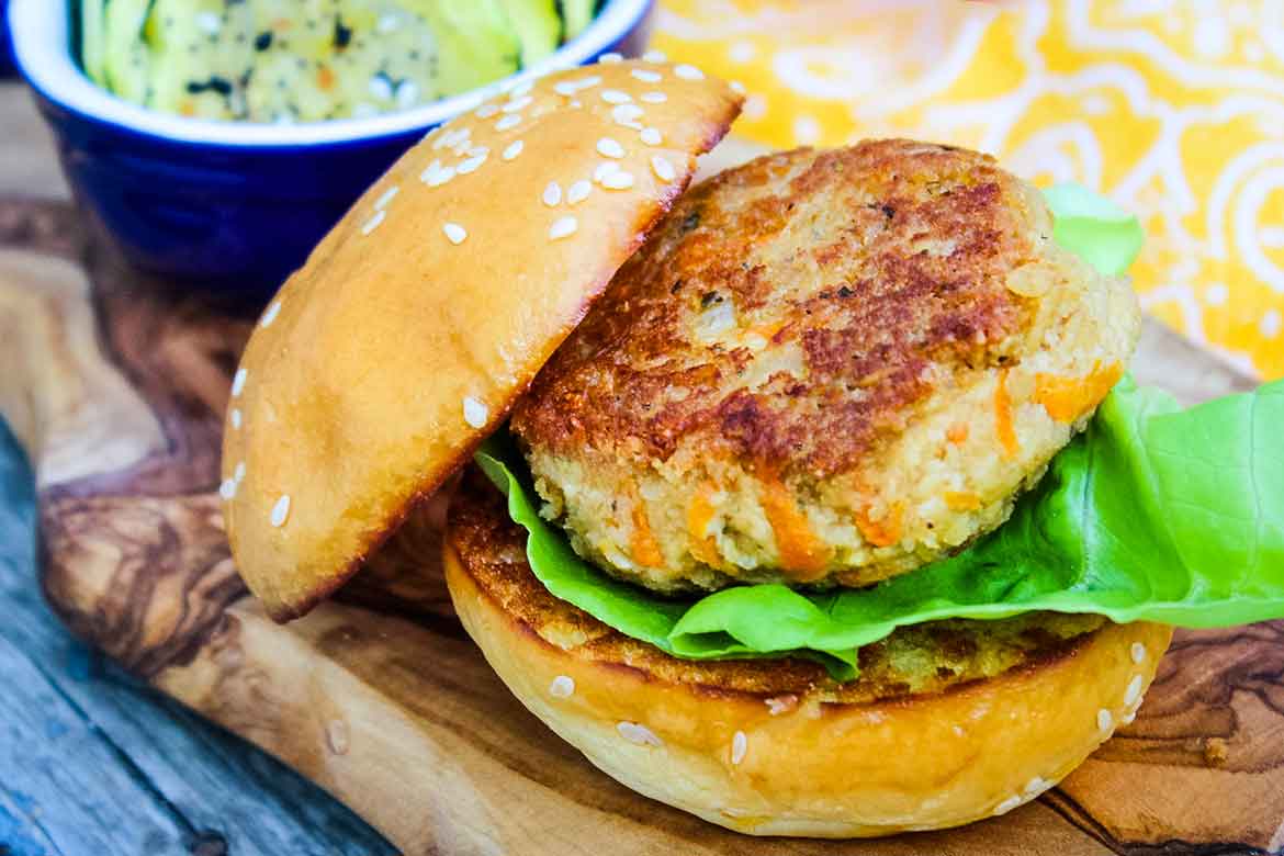 Tofu Burgers made into slider size on a wooden serving tray with zucchini chips in the background.