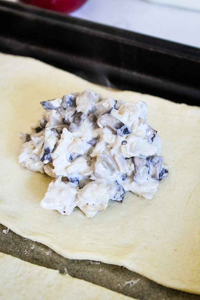 Creamy chicken and mushroom filling on crescent roll dough before shaping into a baseball.
