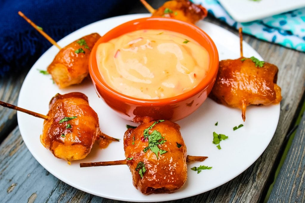 Bacon Wrapped Water Chestnuts with Sweet Chili Sauce on a white plate and extra dipping sauce