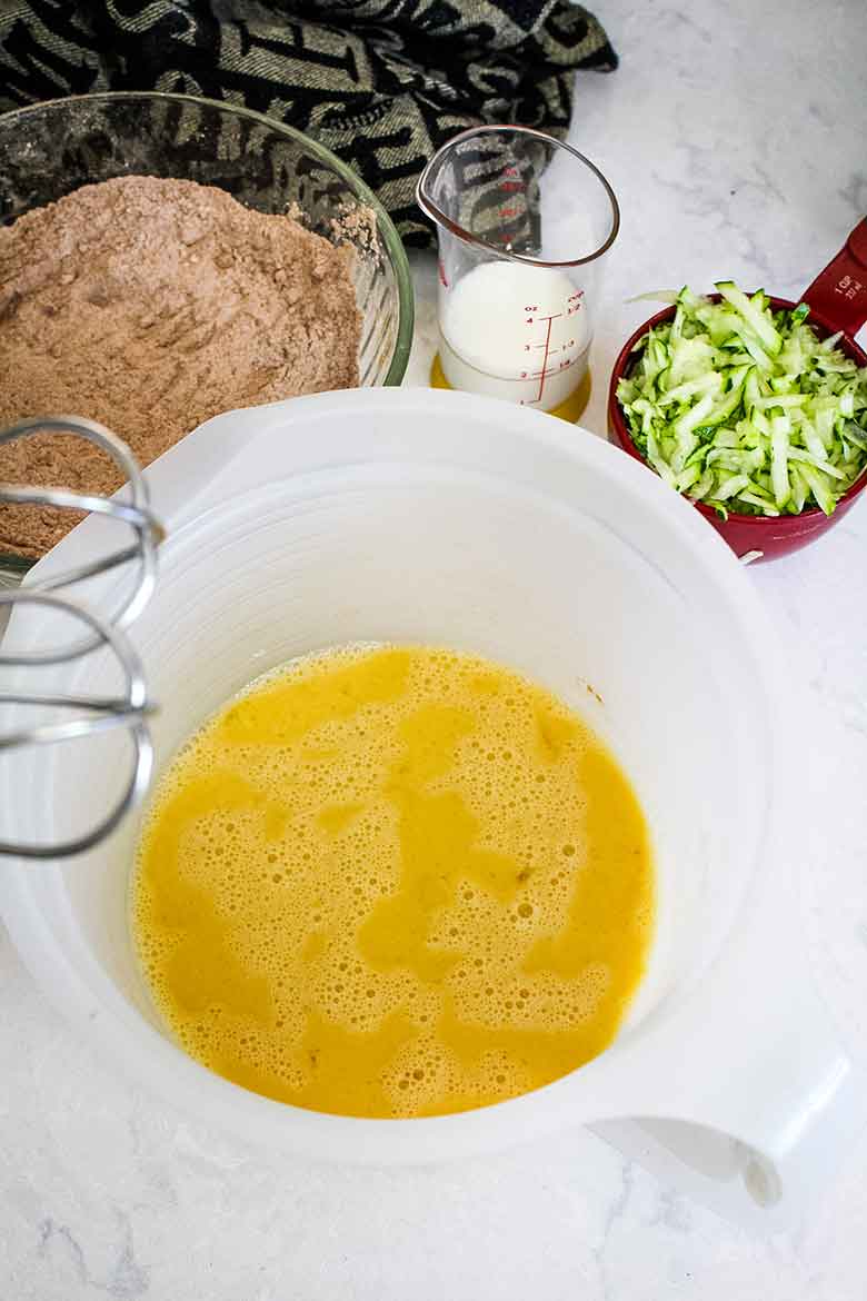 Egg mixture with shredded zucchini and flour mixture ready to combine.