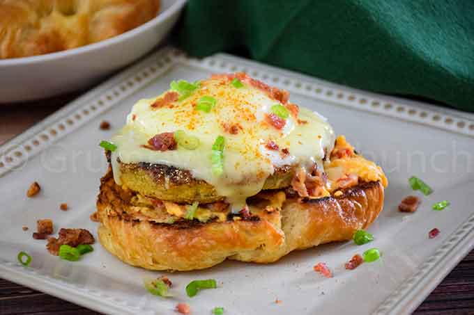 Croissant half topped with pimento cheese, fried tomato, poached egg, hollandaise sauce and bacon crumbles.