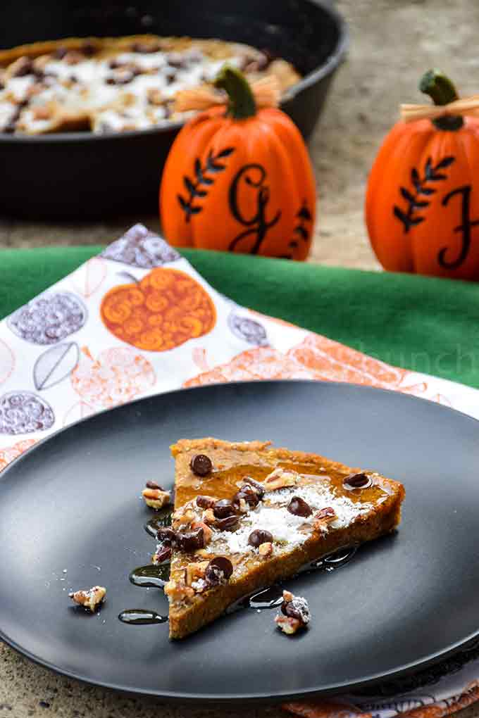 A slice of pumpkin german pancake on a black plate drizzled with sugar free maple syrup