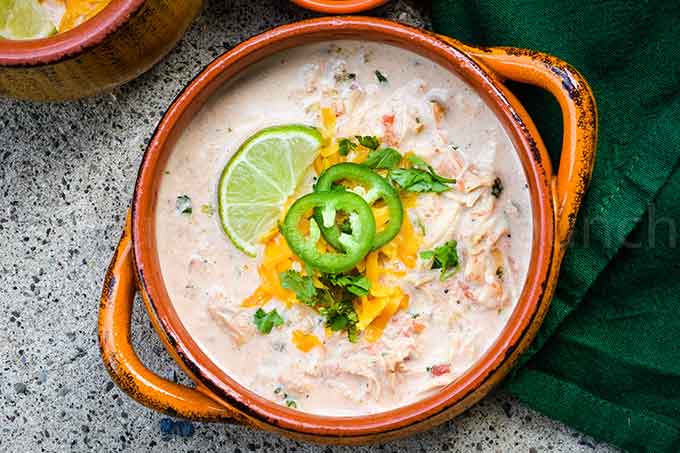 Close up of chicken taco soup in an orange bowl.