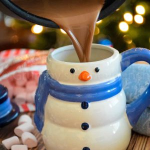 Creamy Hot Cocoa being poured into a snowman mug