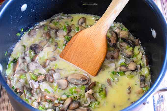 A stockpot with butter, mushrooms, onion, and celery simmering.