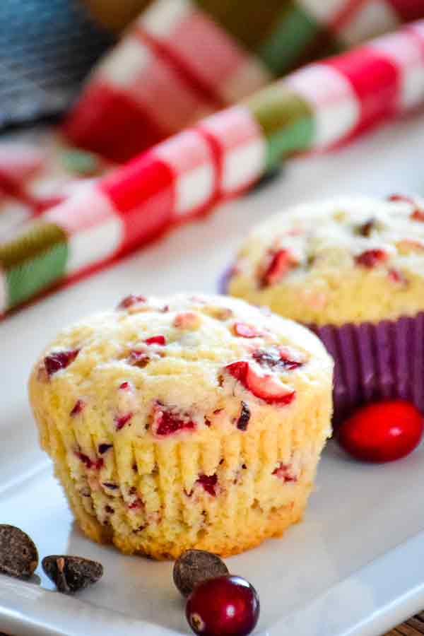 Cranberry chocolate chip Muffins with chocolate and orange on a white plate.