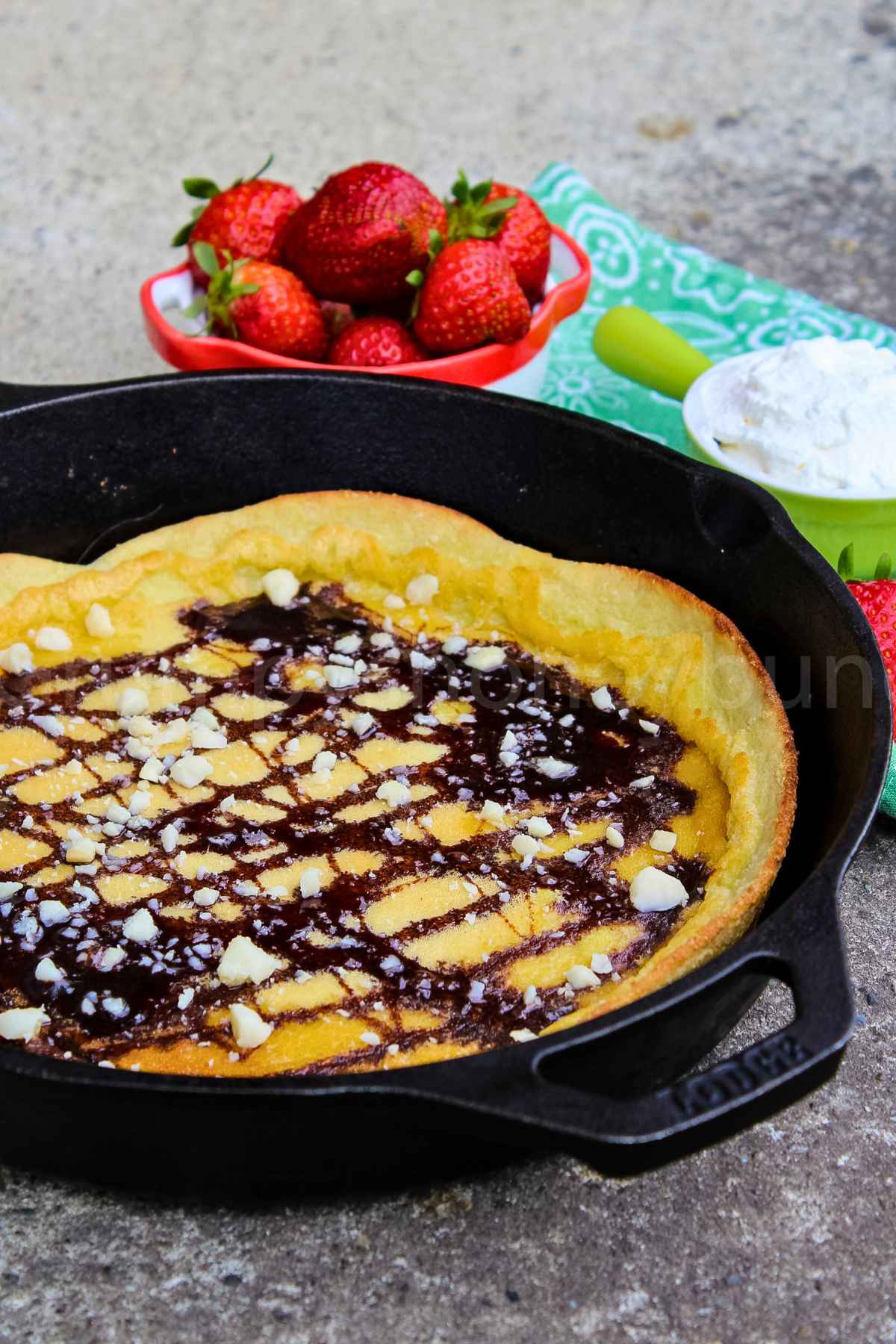 Upclose image of Chocolate Macadamia Keto Dutch Baby in a cast iron skillet.