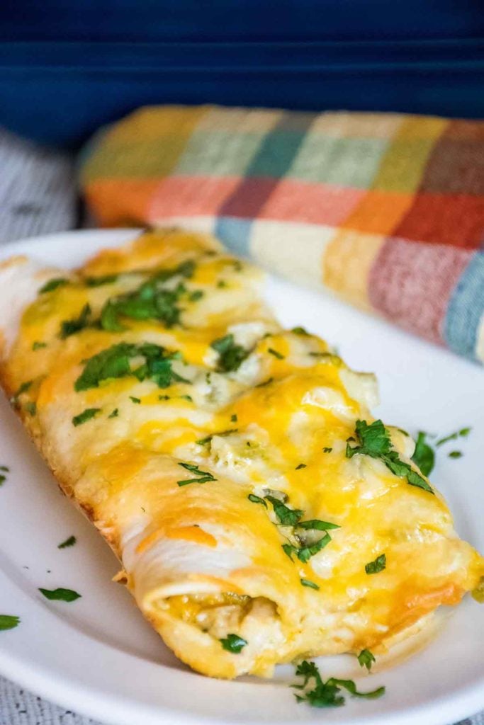 Two low carb green chicken enchiladas on a white plate.