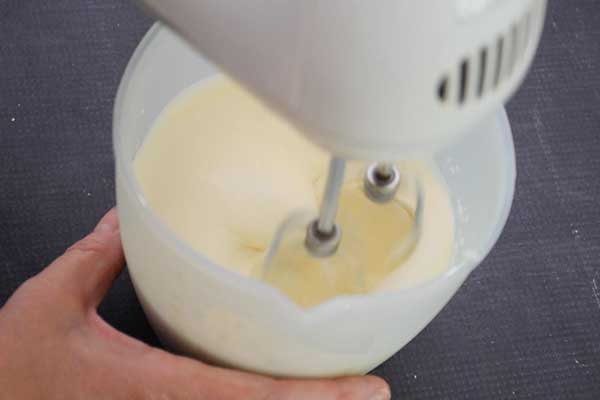 Whipping cream in a bowl with a hand mixer.