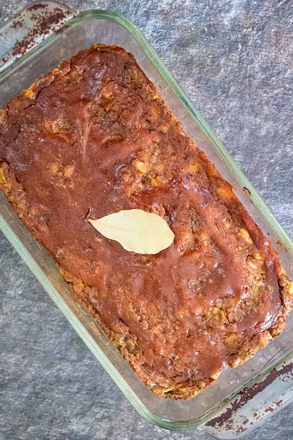 overhead view of baked lentil loaf with sweet and sour topping and a bay leaf on top