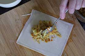 spooning filling to corner of eggroll wrapper