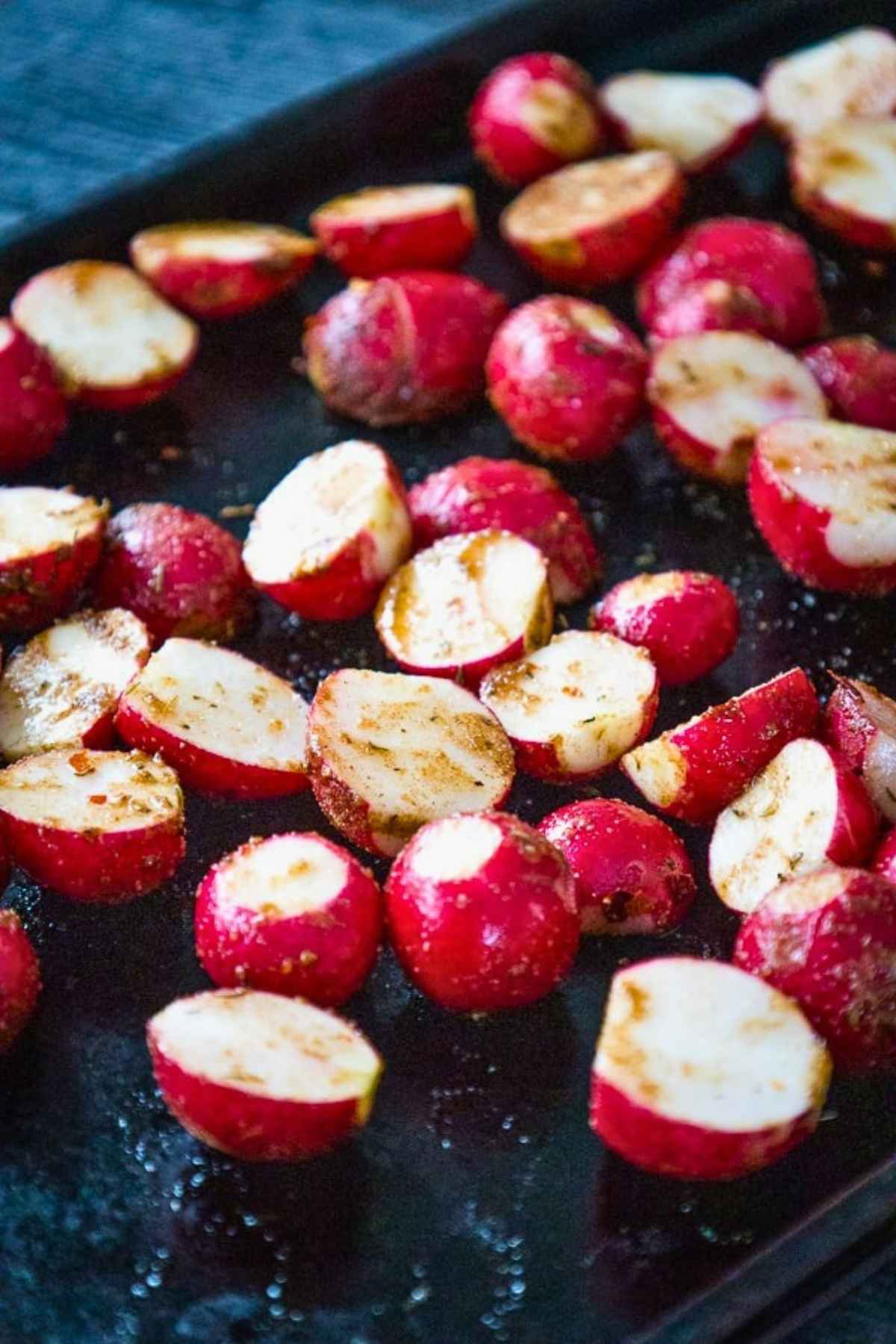 Prepared and seasoned radishes on baking sheet before baking.