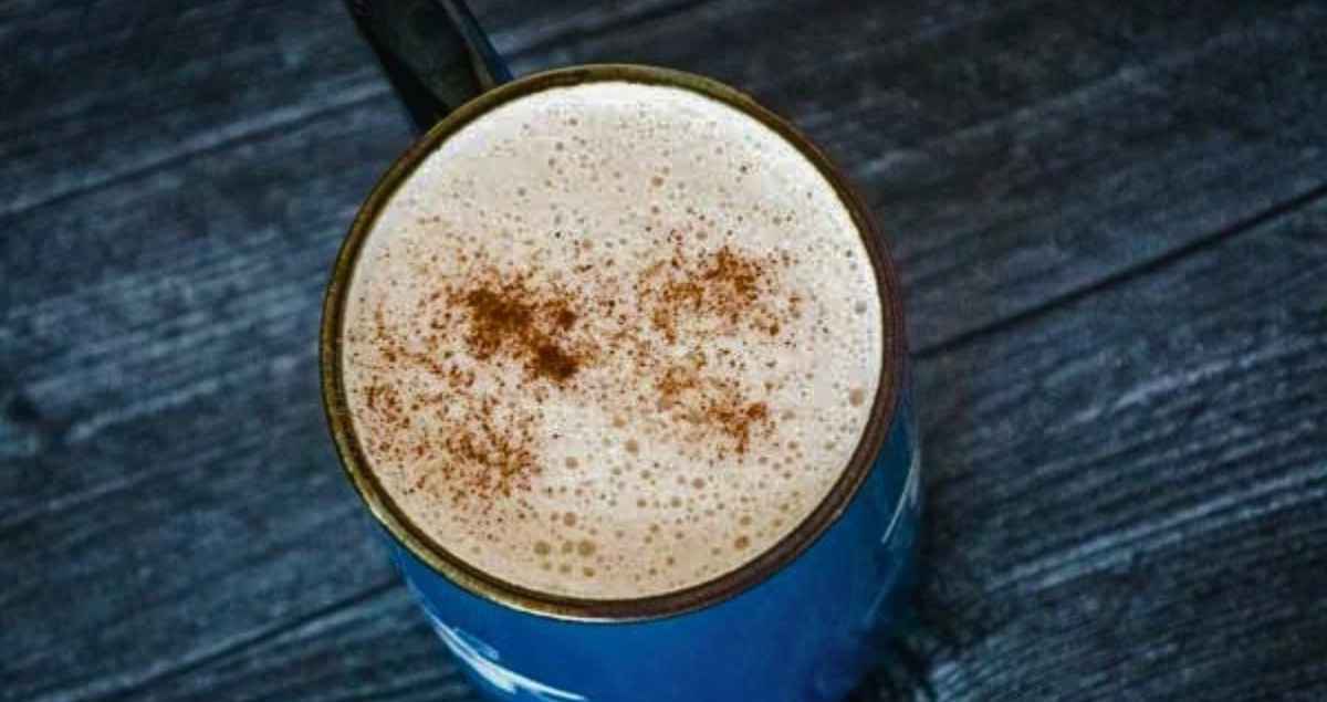 Keto snickerdoodle coffee in a blue mug with cinnamon sprinkled on top.