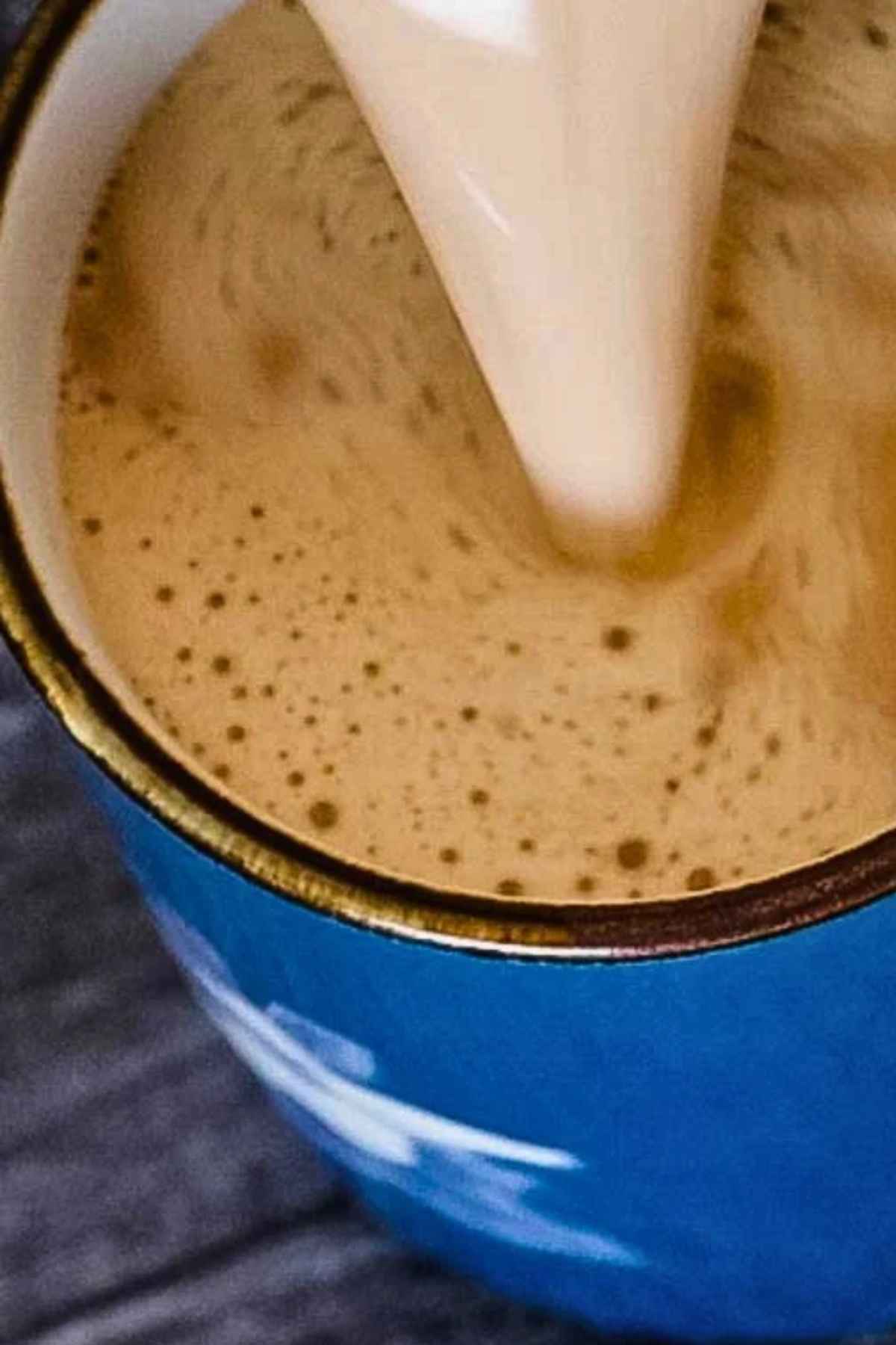 Pouring the keto snickerdoodle coffee into a blue mug.