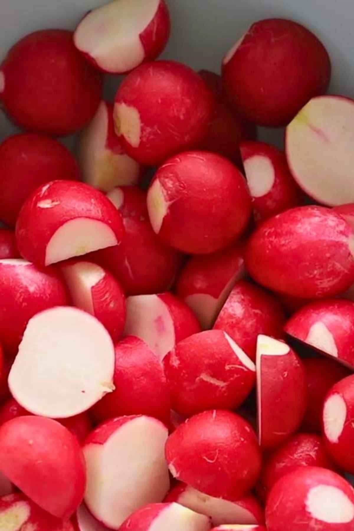 A bowl full of cleaned and halved raw radishes.