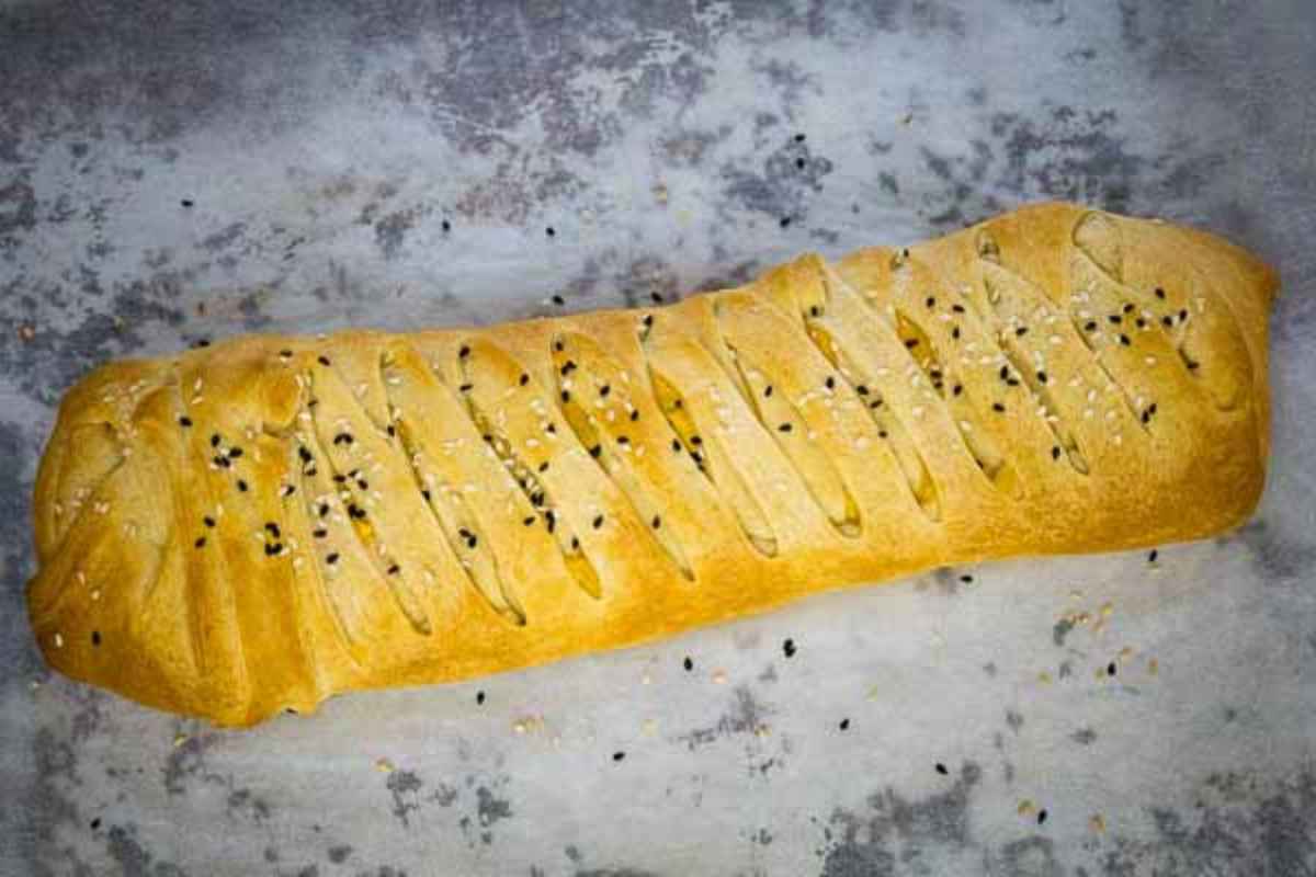 Whole baked crescent braid topped with sesame seeds.
