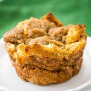 Single croissant French Toast Muffin on a white plate with a green patterned cloth in the background.