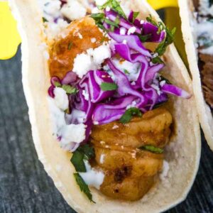 Easy shrimp taco with grilled shrimp, red cabbage slaw, cotija cheese, and cilantro in a soft tortilla.